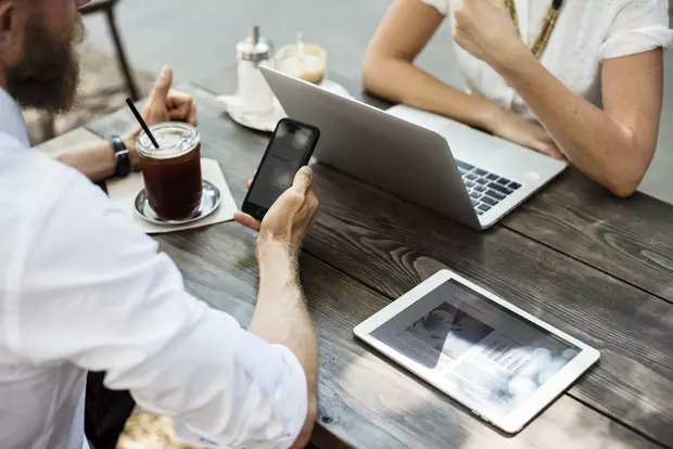 Two people facing each other with smartphone and tablet