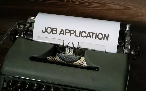 Typewriter containing a sheet of paper with the heading "Job application"